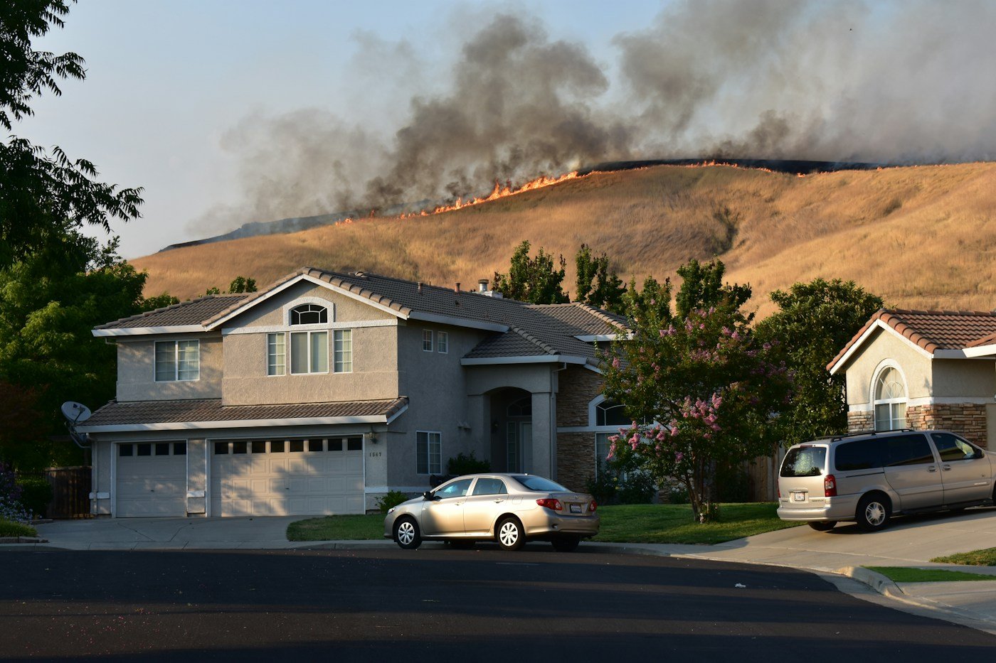 Wildfire burning across a dry hillside near homes, representing a wildfire-related civil claim